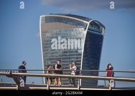 An einem klaren, warmen Tag laufen die Menschen entlang der Millennium Bridge am Walkie Talkie-Gebäude vorbei. London, Großbritannien, 9. Juni 2021. Stockfoto