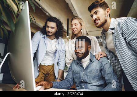 Vier multiethnische Kollegen betrachten im Büro den Computerbildschirm Stockfoto