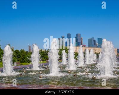 Jets von Springbrunnen an einem sonnigen Tag vor der Kulisse moderner Wolkenkratzer und einem wolkenlosen blauen Himmel. Erholungsgebiet im Victory Park auf Poklonnaya Stockfoto