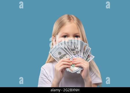 Mädchen hält Banknoten auf Gesichtshöhe Stockfoto