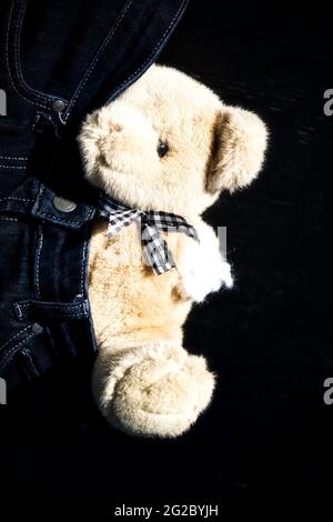 Teddybär Kuscheltier Behinderte mit amputiertem fehlenden Arm, der sich teilweise in Jeans versteckt. Konzept der Gleichheit, Nichtkonformität, anders Stockfoto