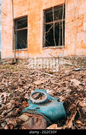 Gasmaske In Der Nähe Des Verlassenen Zerstörten Schulgebäudes Des Alten Dorfes In Der Umsiedlungszone Von Tschernobyl. Weißrussland. Katastrophe Von Tschornobyl. Heruntergekommenes Haus Stockfoto
