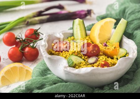 Couscous-Salat mit Gurken, Tomaten und Zwiebeln in einer weißen Schüssel Stockfoto