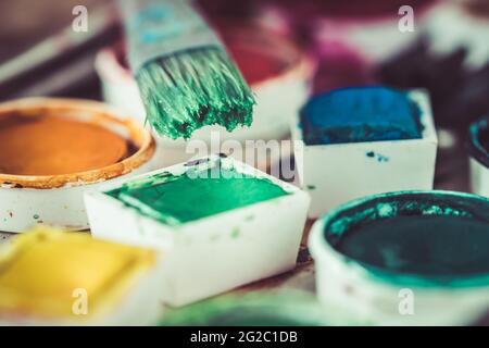 Alte Farbkiste mit bunten Aquarellen, Pinsel mit grüner Farbe Stockfoto