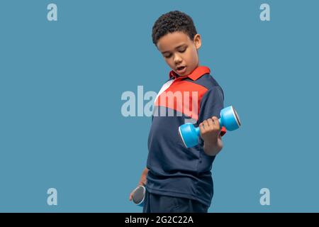 Dunkelhäutig Junge macht Krafttraining mit Hanteln Stockfoto