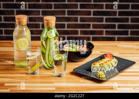 Nahaufnahme von Sushi-Set Sashimi und Sushi-Brötchen, Gurkensaft auf dem Tisch Stockfoto