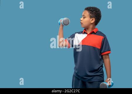 Serious afroamerikanischen Jungen tun Hantel Übung Stockfoto