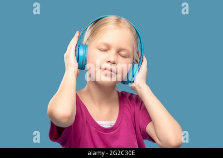 Grundschülerin mit geschlossenen Augen, die Kopfhörer trägt Stockfoto