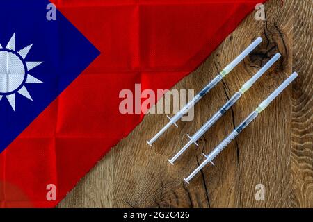 Konzept der laufenden Bemühungen Taiwans, COVID-19-Impfstoffe mit drei Spritzen auf einem gebrauchsfertigen Holztisch zu liefern und zu vertreiben Stockfoto
