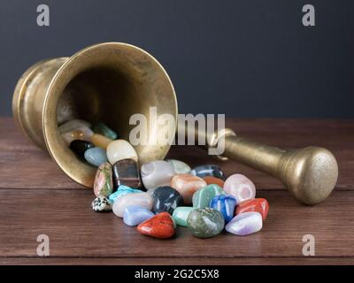 Mörser mit Stößel und vielen Edelsteinen. Konzept der Alchemie, Lithotherapie, Magie Stockfoto