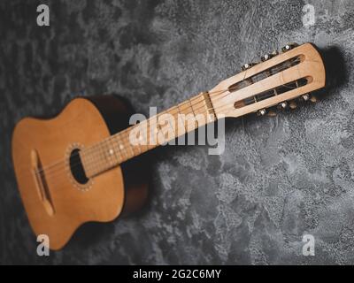 Akustische Gitarre auf dem grauen texturierten Hintergrund. Alte Vintage-Kopfplatte aus der Nähe, selektiver Fokus Stockfoto