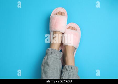 Weibliche Beine in rosa Pantoffeln auf blauem Hintergrund Stockfoto