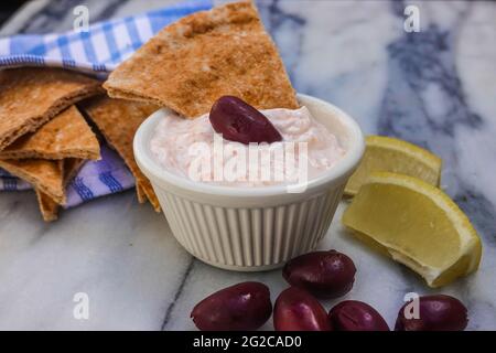 Taramosalata Pita-Brot, kalamata-Oliven und Zitronenkeile auf einer Marmorplatte. Stockfoto