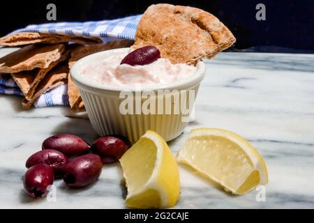 Taramosalata Pita-Brot, kalamata-Oliven und Zitronenkeile auf einer Marmorplatte. Stockfoto