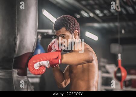 Junge dunkelhäutige Boxerin, die in einem Fitnessstudio trainiert Stockfoto