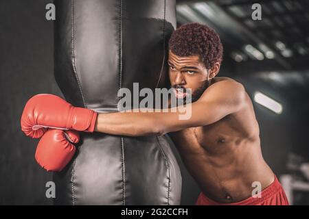 Junge dunkelhäutige Boxerin, die im Fitnessstudio trainiert und müde aussieht Stockfoto