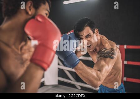 Zwei Kickboxer kämpfen auf einem Boxring und sehen aggressiv aus Stockfoto