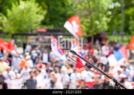 Fokus auf Mikrofon, verschwommene Gruppe von Menschen bei Massenprotesten im Hintergrund Stockfoto