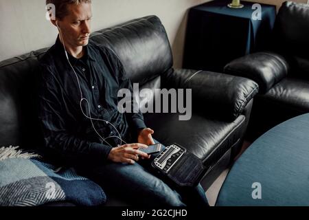 Mann, der auf dem Sofa sitzt und die Brailletastatur benutzt Stockfoto