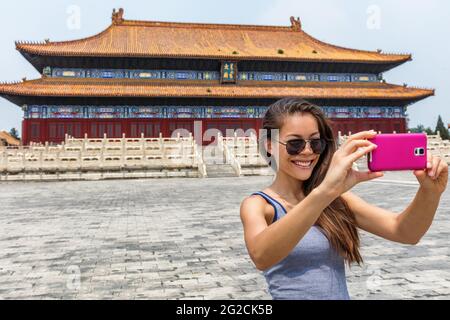 Glücklicher Tourist, der Smartphone-Fotos über Asien macht, reist im Sommer nach china. Junge Frau mit Sonnenbrille macht Selfies Fotos mit Handy Stockfoto