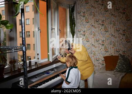 Mutter hört Sohn Keyboard spielen Stockfoto