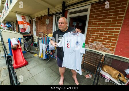 London, Großbritannien. Juni 2021. Chris Dowse, einer der Organisatoren, zeigt stolz sein handsigniertes England-Shirt vom Panama 2018 Turnier - Fußballbegeisterte Bewohner von Bermondseys Kirby Estate im Südosten Londons haben rund 400 England (Kreuz von St. George) Flaggen vor der Europameisterschaft, die an diesem Wochenende beginnt und in der Tat das Covid-verzögerte 2020 Turnier ist. Kredit: Guy Bell/Alamy Live Nachrichten Stockfoto