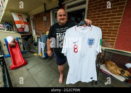 London, Großbritannien. Juni 2021. Chris Dowse, einer der Organisatoren, zeigt stolz sein handsigniertes England-Shirt vom Panama 2018 Turnier - Fußballbegeisterte Bewohner von Bermondseys Kirby Estate im Südosten Londons haben rund 400 England (Kreuz von St. George) Flaggen vor der Europameisterschaft, die an diesem Wochenende beginnt und in der Tat das Covid-verzögerte 2020 Turnier ist. Kredit: Guy Bell/Alamy Live Nachrichten Stockfoto