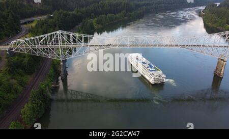 Luftaufnahme eines Ausflugsschiffs, das unter der Bridge of the Gods am Columbia River in Cascade Locks, Oregon, vorbeifährt Stockfoto