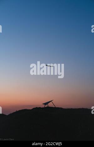 Silhouette eines Flugzeugs, das während des Sonnenuntergangs über einem Berg fliegt Stockfoto