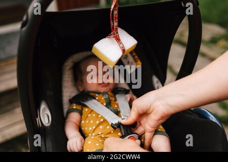 Die Hände der Mutter knicken das Baby im Babyschaukel Stockfoto