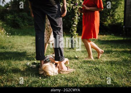 Mädchen liegt auf dem Rasen zwischen den Füßen des Vaters Stockfoto