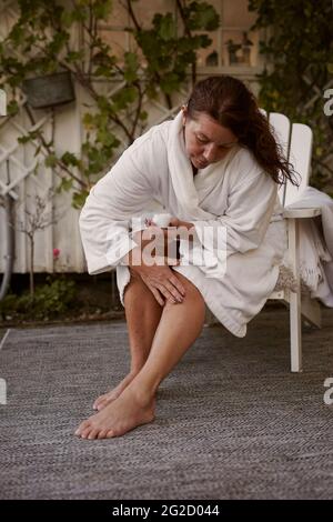 Frau im Garten Anwendung Feuchtigkeitscreme Stockfoto