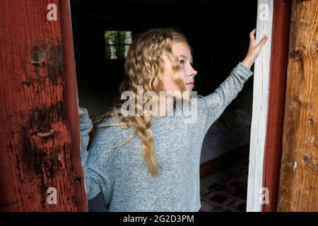 Blonde Mädchen vorbei Holztür Stockfoto