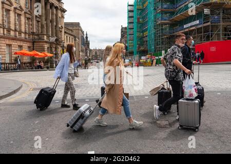 Edinburgh, Schottland, Großbritannien. 10. Juni 2021. Aufgrund der Reisebeschränkungen des Coronavirus sind viele Touristenläden auf der Royal Mile geschlossen oder leiden unter finanziellen Schwierigkeiten. Viele haben Schilder in die Fenster gesetzt, in denen sie die schottische SNP-Regierung beschuldigen, nicht genug getan zu haben, um Arbeitsplätze zu retten. PIC; Gruppe von Chinesen mit Koffern auf der Royal Mile. Iain Masterton/Alamy Live News Stockfoto