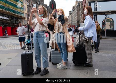 Edinburgh, Schottland, Großbritannien. 10. Juni 2021. Aufgrund der Reisebeschränkungen des Coronavirus sind viele Touristenläden auf der Royal Mile geschlossen oder leiden unter finanziellen Schwierigkeiten. Viele haben Schilder in die Fenster gesetzt, in denen sie die schottische SNP-Regierung beschuldigen, nicht genug getan zu haben, um Arbeitsplätze zu retten. PIC; Gruppe von Chinesen mit Koffern auf der Royal Mile. Iain Masterton/Alamy Live News Stockfoto