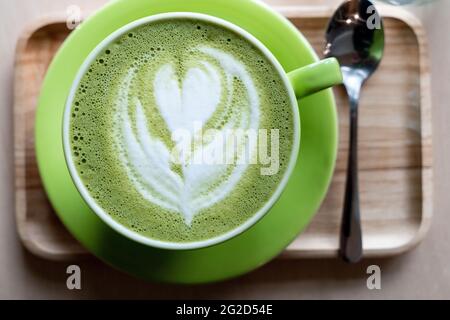 Matcha Latte mit Herz in einer grünen Tasse in einem Café Stockfoto