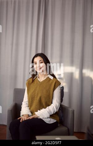 Lächelnde junge Frau im Sessel sitzen Stockfoto