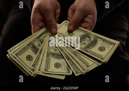 In den Händen ältere oder ältere Frau mit US-Dollar-Banknoten Geld auf schwarzem Hintergrund Stockfoto