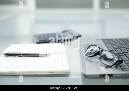 Stift Notizblock Taschenrechner Brille Notebook auf Glastisch im Büro Stockfoto