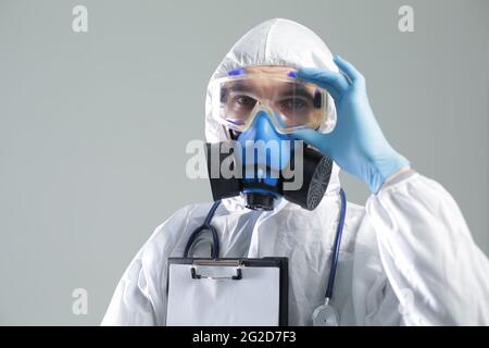 Arzt mit Schutzmaske, Brille und Anzug mit Stethoskop und Thermometer Stockfoto