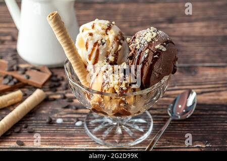 Schokolade, Rahm und Karamell-Roma-Eis in einer Glasschüssel mit Haselnuss- und Schokoladensauce darüber gegossen. Stockfoto