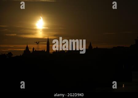 Ottawa, Kanada. 10. Juni 2021: Eine partielle Sonnenfinsternis wird am Donnerstag, 10. Juni 2021, über dem Parliament Hill in Ottawa, Kanada, gesehen. Die ringförmige oder „Feuerring“-Sonnenfinsternis ist nur für einige Menschen in Grönland, Nordrussland und Kanada sichtbar. In Kanadas National Capital Region lag die Sonne am Höhepunkt der Sonnenfinsternis weniger als 3 Grad über dem Horizont, sichtbar nur als schmale Sichel mit den landschaftlich reizvollen Regierungsgebäuden des Landes, die einen dramatischen Hintergrund bieten. Quelle: George Ross/Alamy Live News Stockfoto