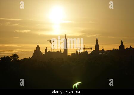 Ottawa, Kanada. 10. Juni 2021: Eine partielle Sonnenfinsternis wird am Donnerstag, 10. Juni 2021, über dem Parliament Hill in Ottawa, Kanada, gesehen. Die ringförmige oder „Feuerring“-Sonnenfinsternis ist nur für einige Menschen in Grönland, Nordrussland und Kanada sichtbar. In Kanadas National Capital Region lag die Sonne am Höhepunkt der Sonnenfinsternis weniger als 3 Grad über dem Horizont, sichtbar nur als schmale Sichel mit den landschaftlich reizvollen Regierungsgebäuden des Landes, die einen dramatischen Hintergrund bieten. Quelle: George Ross/Alamy Live News Stockfoto