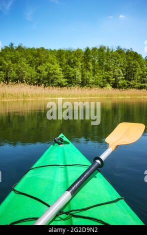 Paddeln Sie auf einem Bogen eines grünen Kajaks im Wasser, selektiver Fokus. Stockfoto