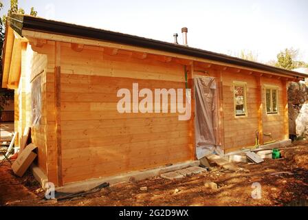 Ein neu erbautes, aber unvollständiges Holzhaus (Tanne) mit Regenrinnen und montierten Fenstern. Provinz Udine,Friaul-Julisch Venetien,Italien Stockfoto