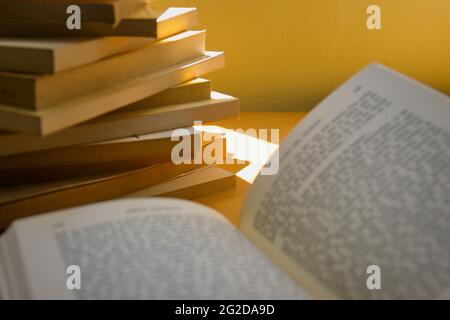 Bild eines offenen Lesebuchs aber der Text ist unscharf im Hintergrund sieht man viele Bücher Stockfoto