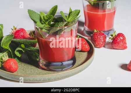 Frischer Erdbeersaft, kalter Sommerbeercocktail mit Minze in Gläsern, gesunde natürliche Nahrung, Nahaufnahme, raue Beleuchtung Stockfoto