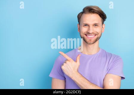Foto-Porträt von Kerl zeigt Finger Copyspace empfehlen isoliert auf pastellblauen Hintergrund Stockfoto