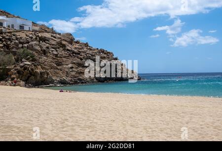 Mykonos Island, Kykladen. Griechenland. Super Paradise Sandstrand, Sommerurlaub Karte und Werbevorlage. Weißes Gebäude auf dem felsigen Hügel, Wolke Stockfoto