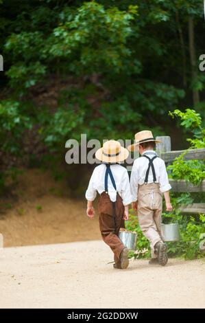 Zwei Jungen in der Zeit Kostüm Wandern mit Mittagessen Eimer, Old Sturbridge Village, Sturbridge, Massachusetts Stockfoto